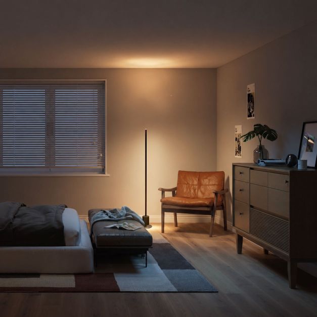 Modern bedroom with a bed, chair, and dresser under warm lighting.