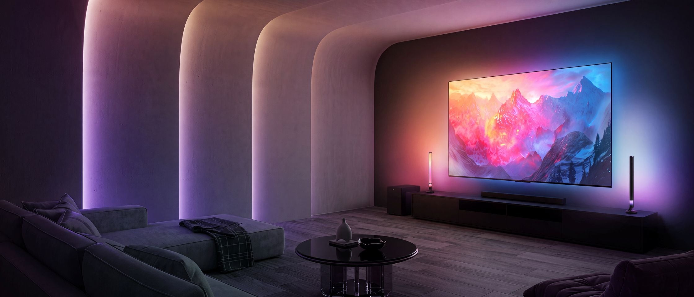 A large wall-mounted television displaying a colorful mountain landscape, set in a modern home theater with curved walls, ambient purple lighting, a sofa, and a coffee table.